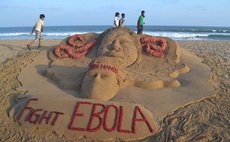 BHUBANESWAR, Aug. 20, 2014 (Xinhua) -- Visitors walk past a sand sculpture to fight against EBOLA virus created by Sudarshan Pattnaik at Puri beach, India, Aug. 19, 2014