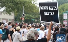 A woman holds up a BlackLives Matter sign at the Michael Brown memorial in Ferguson, Missouri, U.S., on August 9, 2015. 