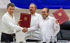 Colombian President Juan Manuel Santos (L) and Timoleon Jimenez (R), the top leader of the Revolutionary Armed Forces of Colombia (FARC), exchange pacts while Cuban President Raul Castro witnesses 