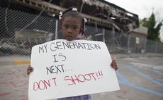 FERGUSON, Aug. 16, 2014 (Xinhua) -- A girl holds a placard during a protest in Ferguson, Missouri, on Aug. 15, 2014. Police in Ferguson in the U.S. state of Missouri