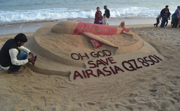 BHUBANESWAR, Dec. 28, 2014 (Xinhua) -- Sand artist Sudarshan Pattnaik (L) decorates a sand art of the missing AirAsia plane at the Bay of Bengal Sea's,  India, Dec. 28, 2014. 