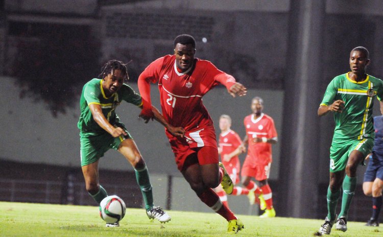 Battle for the ball:Canada in red, Dominica in green