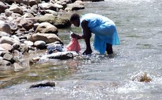A woman washes her clothes in the Roseau River