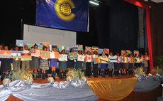 Students hold up maps of Commonwealth countries at the Arawak House of Culture during Commonwealth Day Ceremony
