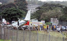 Officials examine plane crash; Morne Daniel house in the background