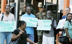 Dr. Fontaine,left, Edison James, centre, and others hold placards at the UWP protest this morning