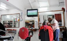 A Haitian barber shaves a client at a shop on Hillsborough Street