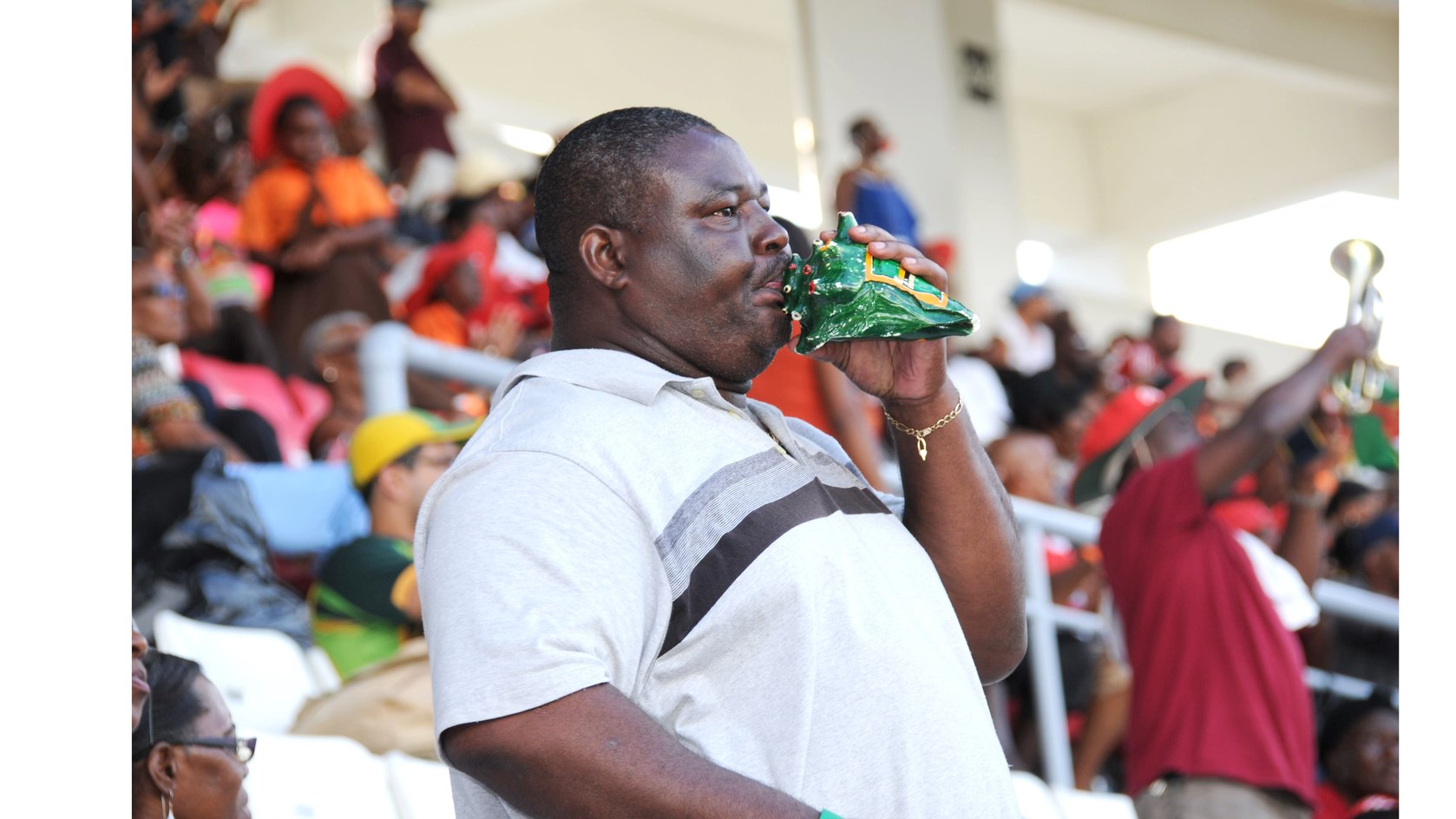  A man blows a conch shell during a cricket match at the Windsor Park