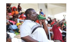  A man blows a conch shell during a cricket match at the Windsor Park 