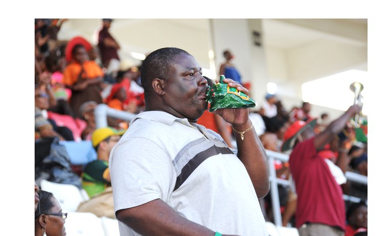  A man blows a conch shell during a cricket match at the Windsor Park