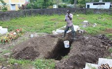 Gravedigger removes buckets of water from grave at Catholic Cemetery , Roseau