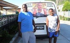 Edward Morancie, left, and grandson stand before bus with photo of Nashum Attidore on windshield