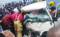 Crowd look on at damaged vehicles