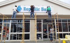Workmen about to erect Republic Bank name sign name 